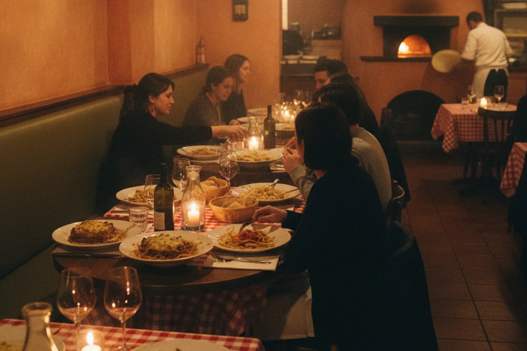 Warm erleuchteter Gastraum der Trattoria am Abend, Gäste am Tisch